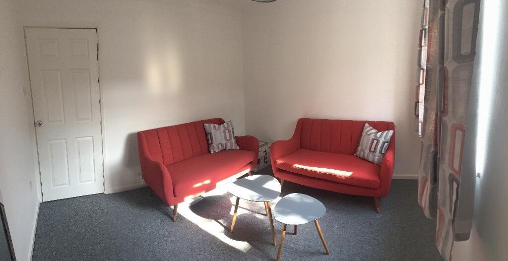 Bright, tidy living room with matching red two-...