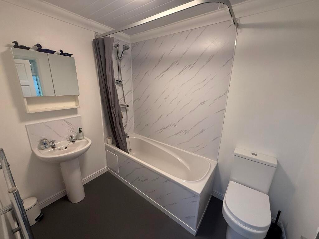 Bright, modern bathroom featuring a bathtub wit...