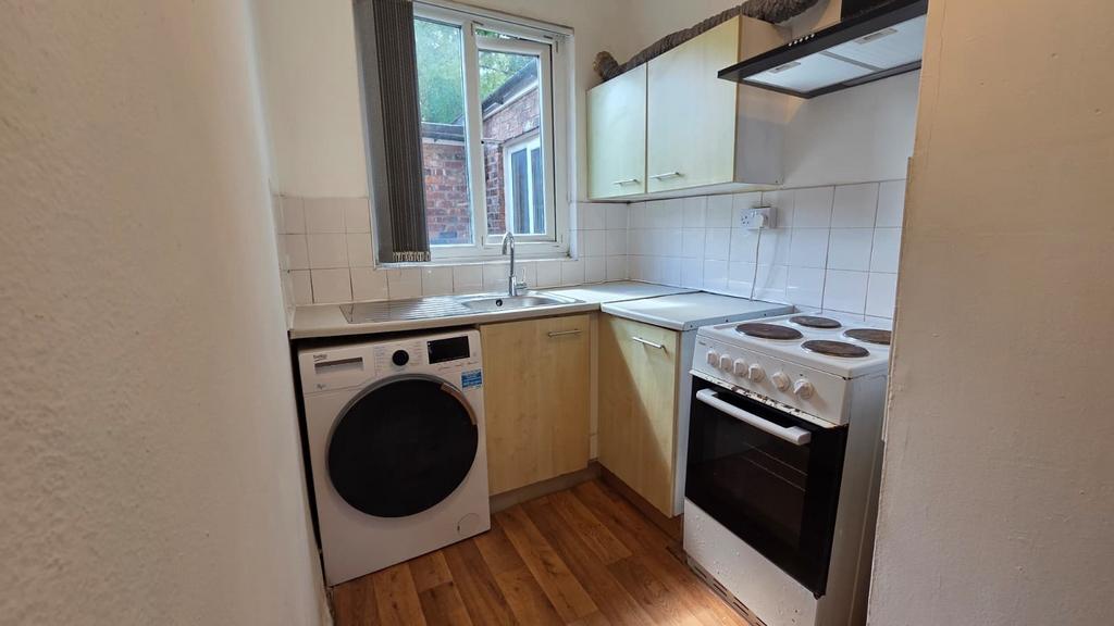 Compact fitted kitchen with a sink under a wind...