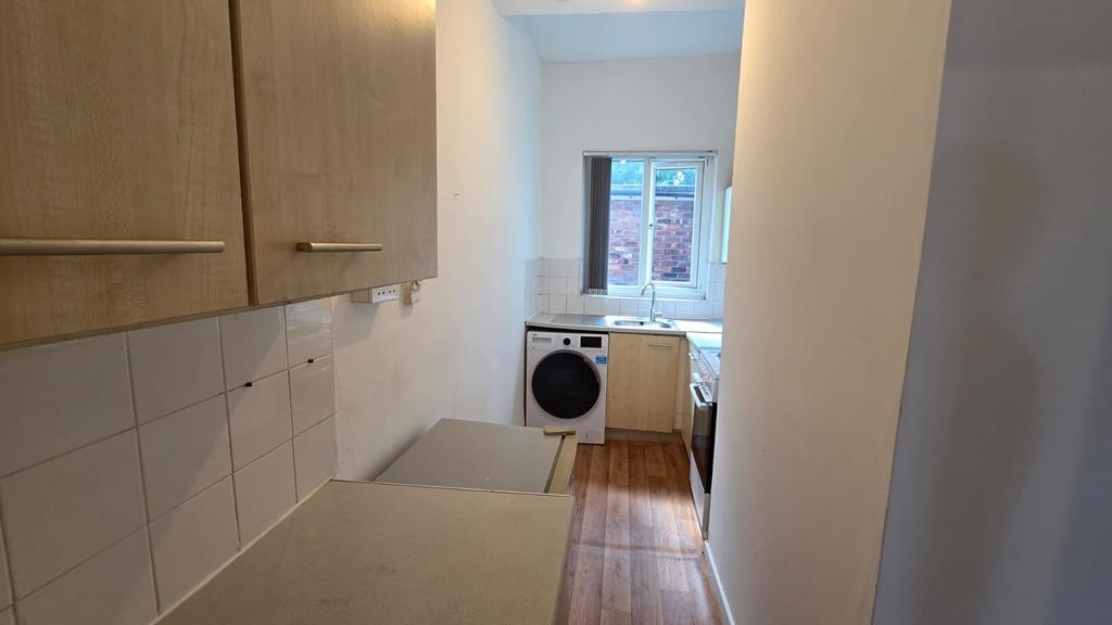 Compact galley kitchen with light wood cabinets...