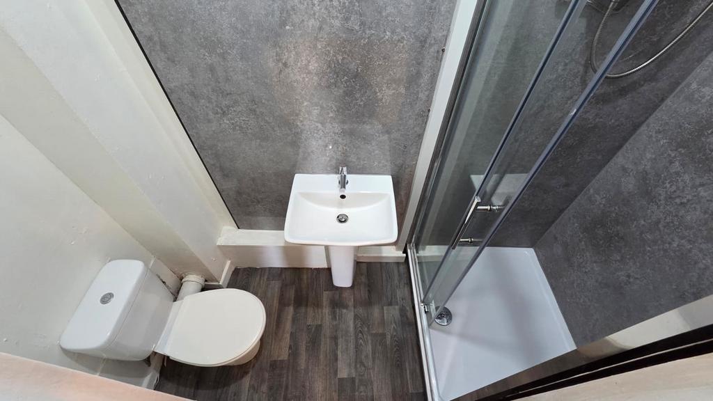 Compact modern bathroom with a corner shower en...