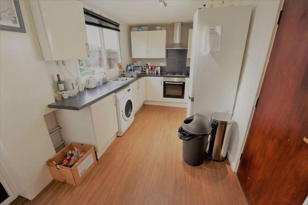 Bright galley-style kitchen with white cabinetr...