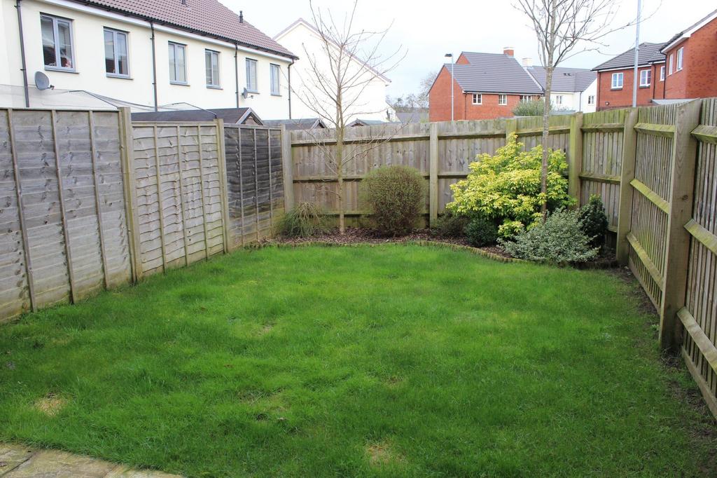 Enclosed rear garden with a well-kept lawn, mat...