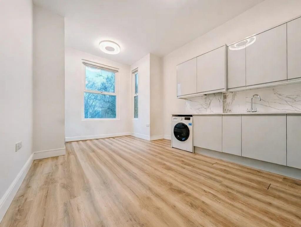 Bright, modern kitchen area with sleek white ca...