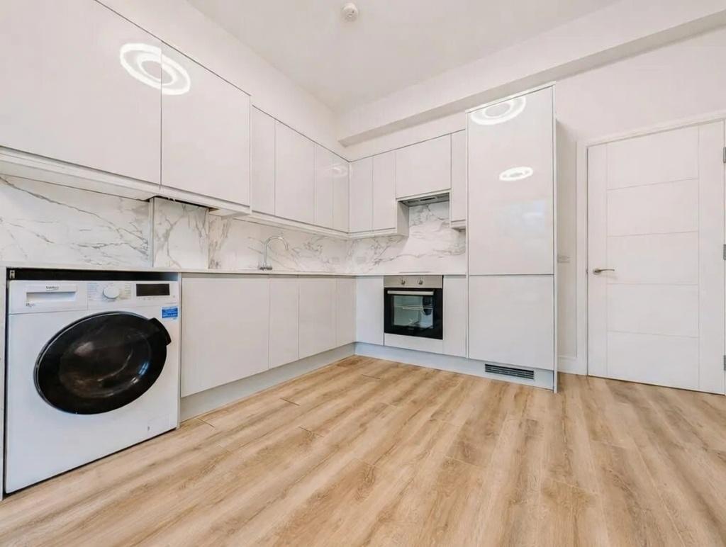 Bright modern kitchen with white cabinetry, int...