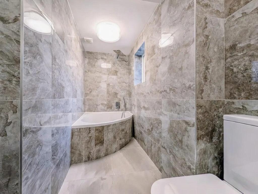 Modern tiled bathroom with a curved bathtub, sl...