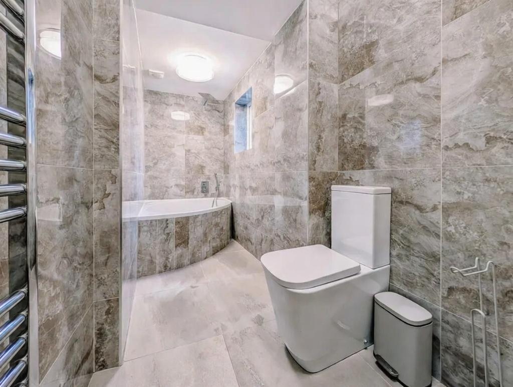 Modern bathroom with marble-effect tiled walls ...