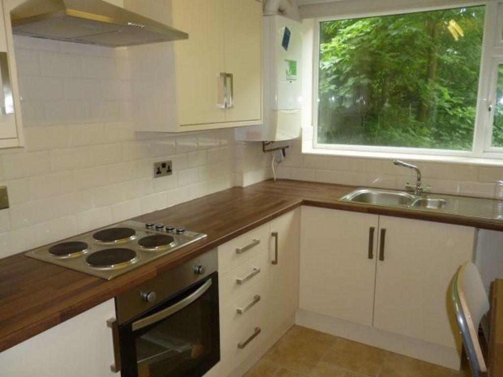Bright fitted kitchen with white cabinetry, woo...