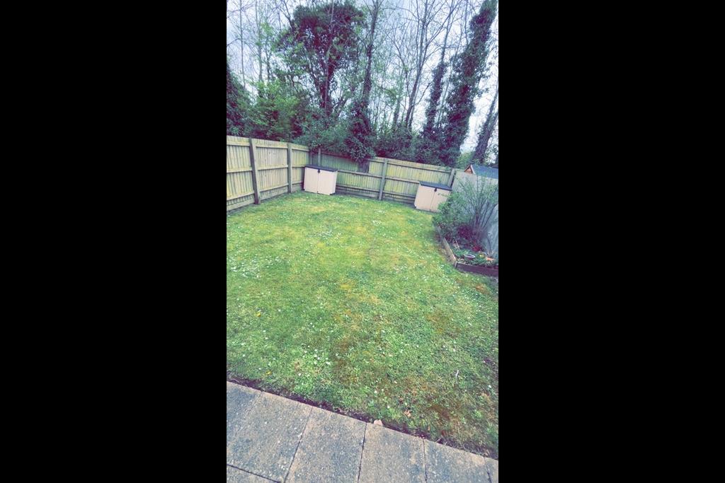 Enclosed rear garden with a neat lawn, timber f...