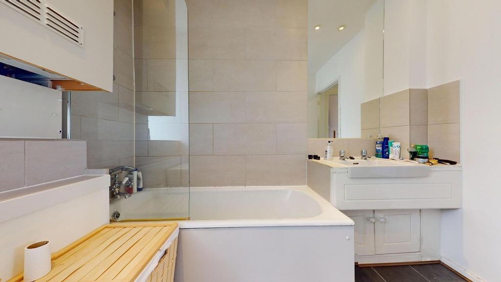 Bright, modern bathroom with a tiled bath and g...