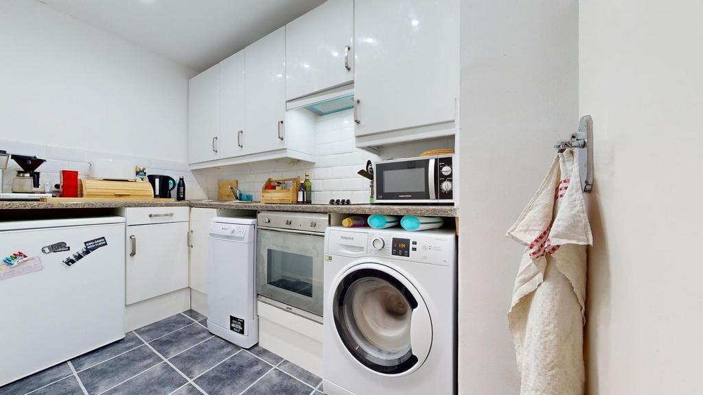 Bright, modern kitchen with white cabinetry, ti...