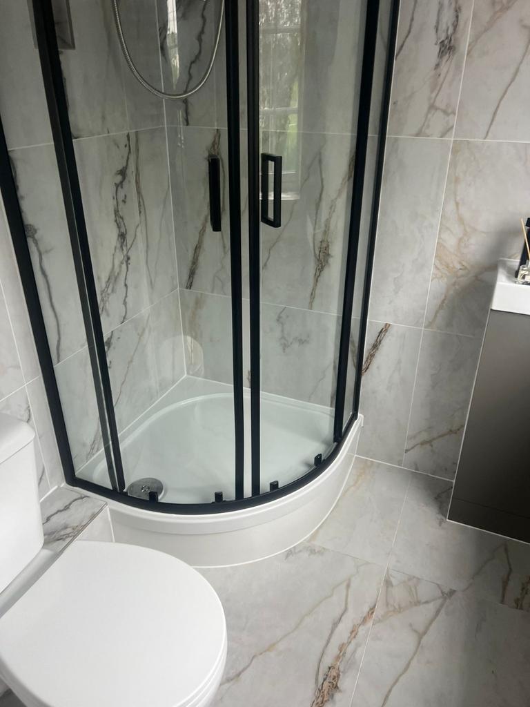 Modern tiled bathroom with a curved glass showe...