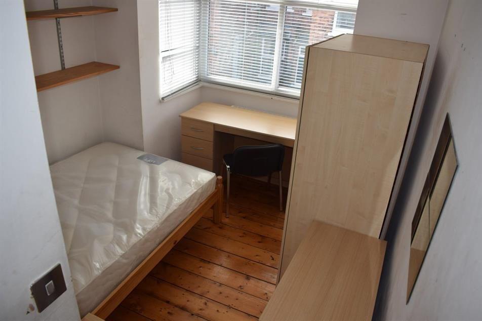 Bright, simply furnished bedroom with a single ...