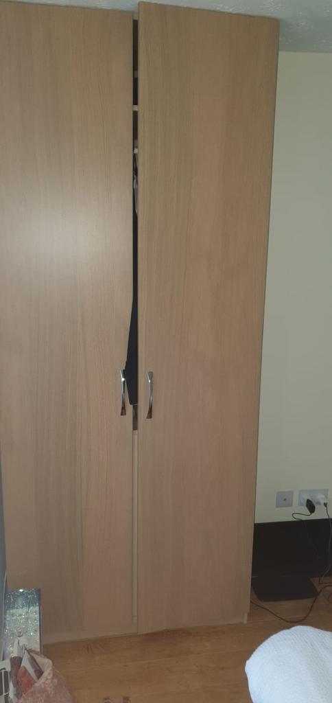 A simple wooden double-door wardrobe in a tidy ...