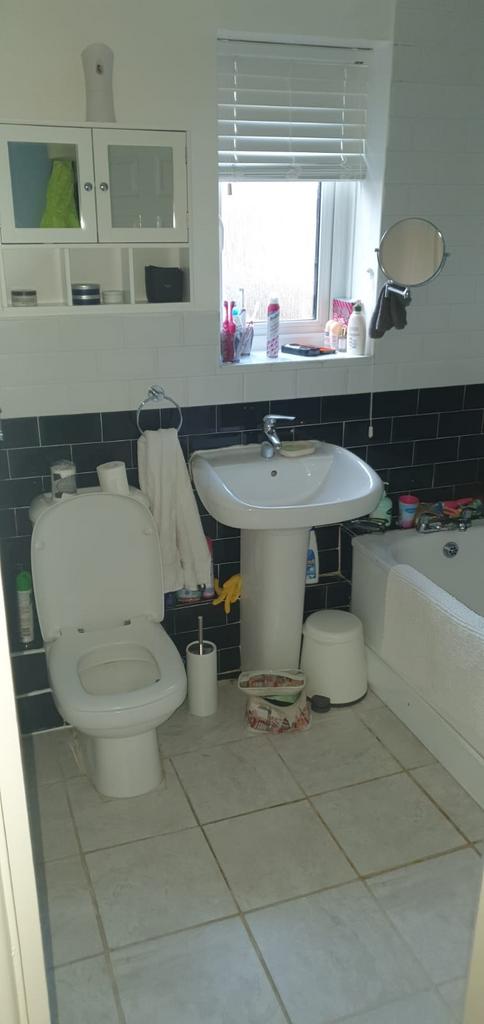 Bright, tiled bathroom with a pedestal sink, ba...