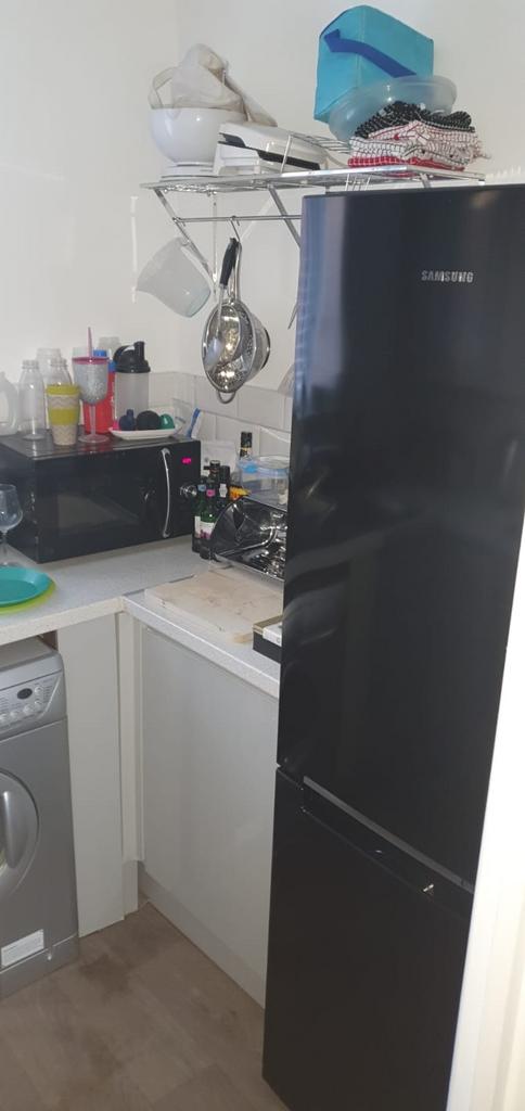 Compact fitted kitchen with a tall black Samsun...