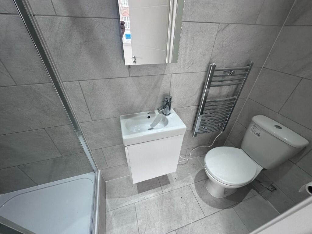 Modern tiled bathroom with a corner shower, com...