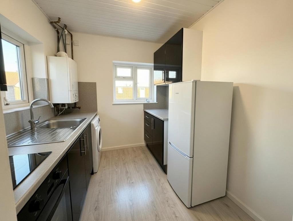 Bright galley-style kitchen with modern dark ca...