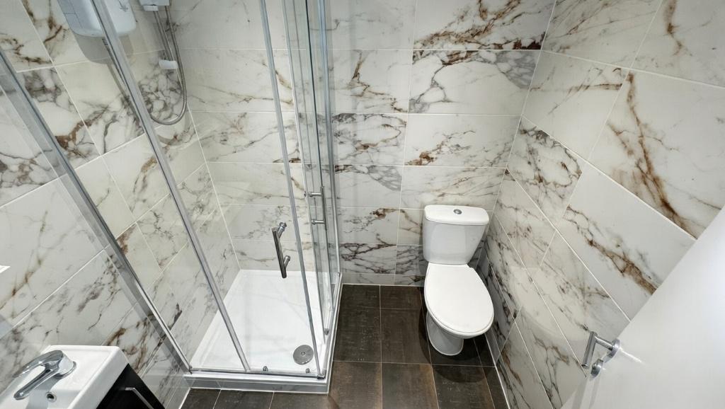 Modern bathroom with a glass-enclosed shower, s...