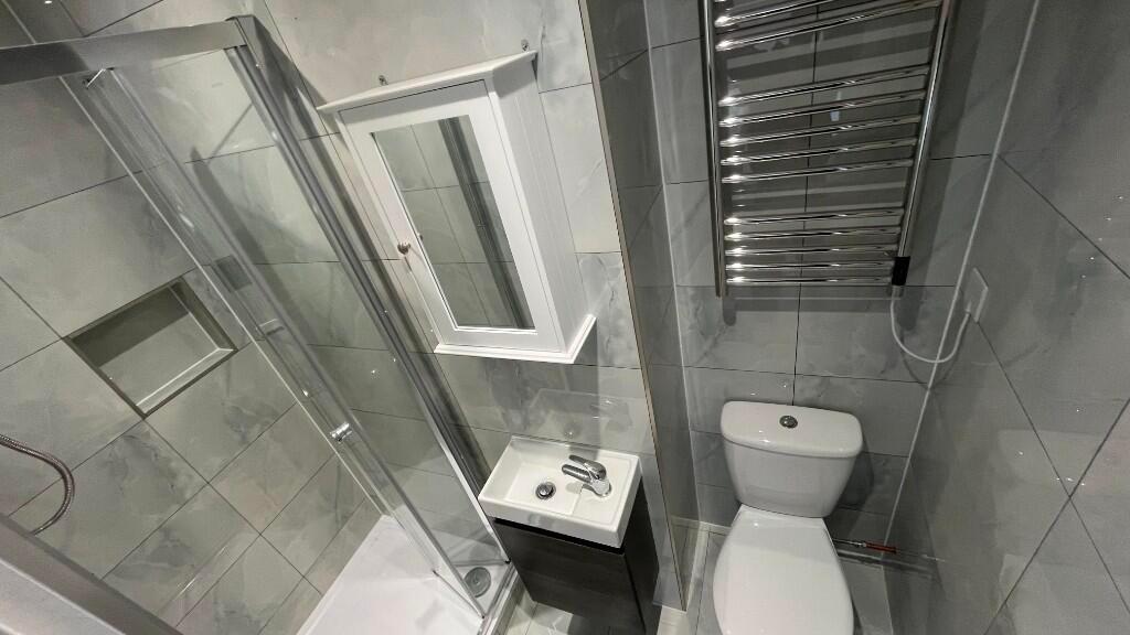 Modern tiled bathroom with a glass shower enclo...