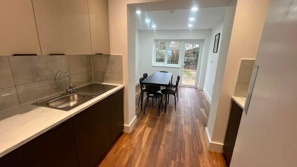 Modern galley kitchen opening into a bright din...