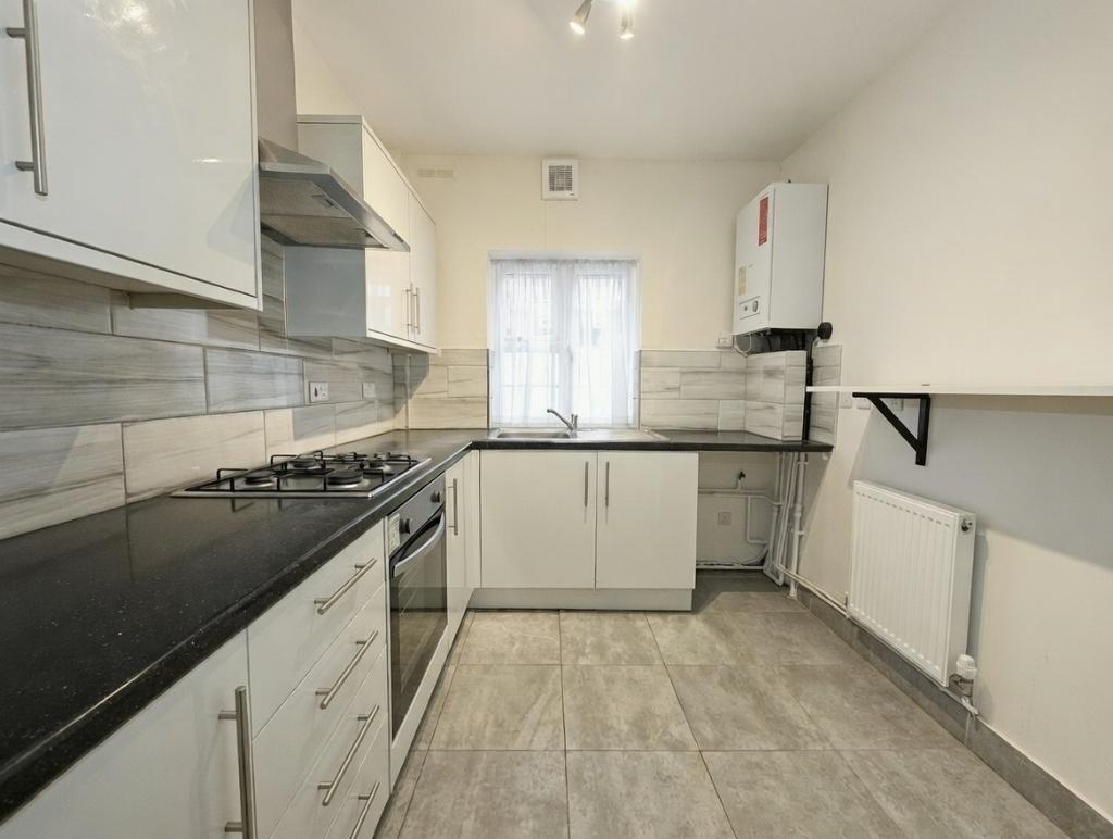 Modern galley kitchen with white cabinetry, int...