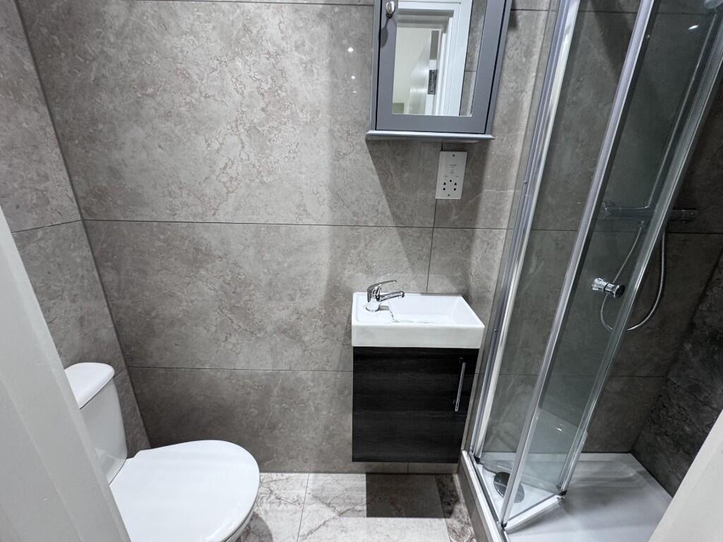 Modern tiled bathroom with a corner glass showe...