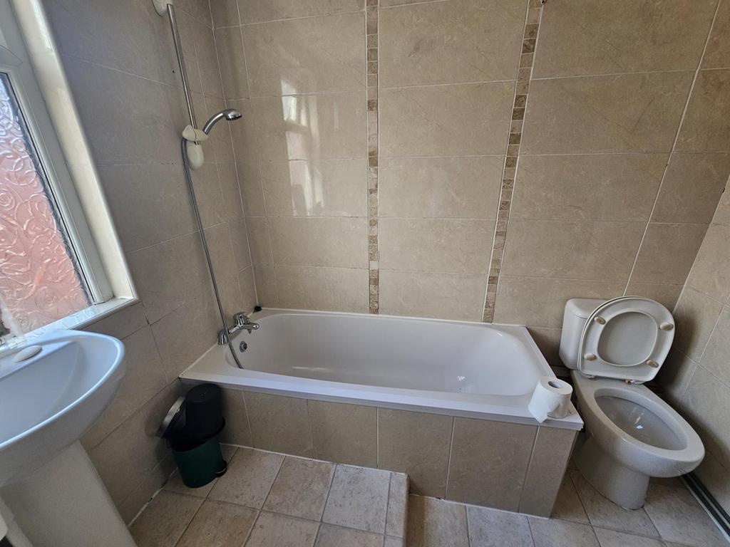 Bright tiled bathroom with a bathtub and overhe...
