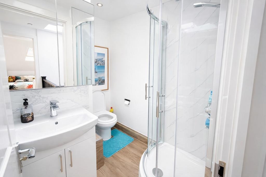 Bright, modern bathroom with a curved glass sho...