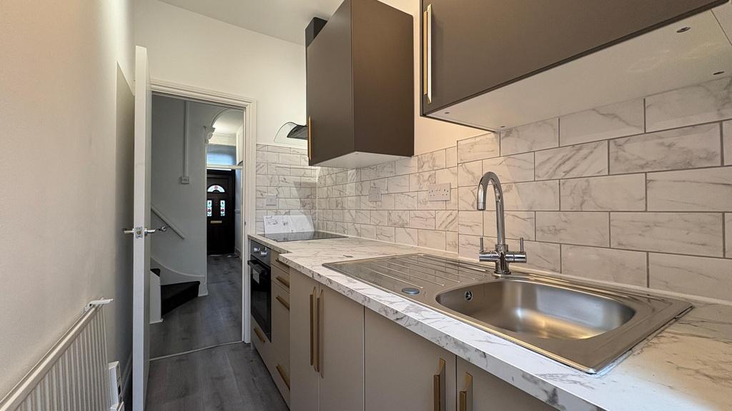 Bright galley kitchen with modern cabinetry, in...
