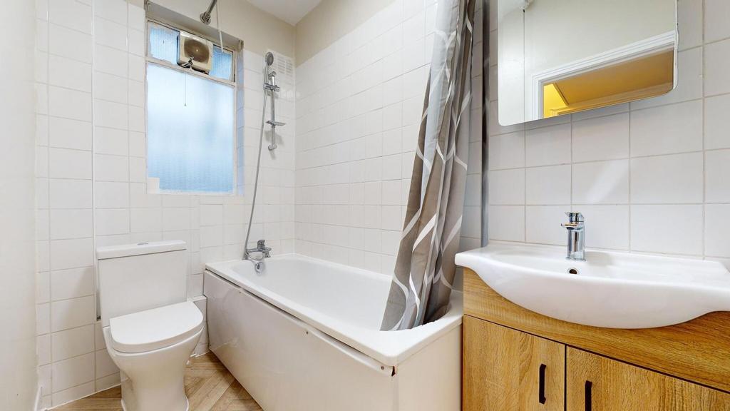 Bright, tiled bathroom with a bathtub and overh...