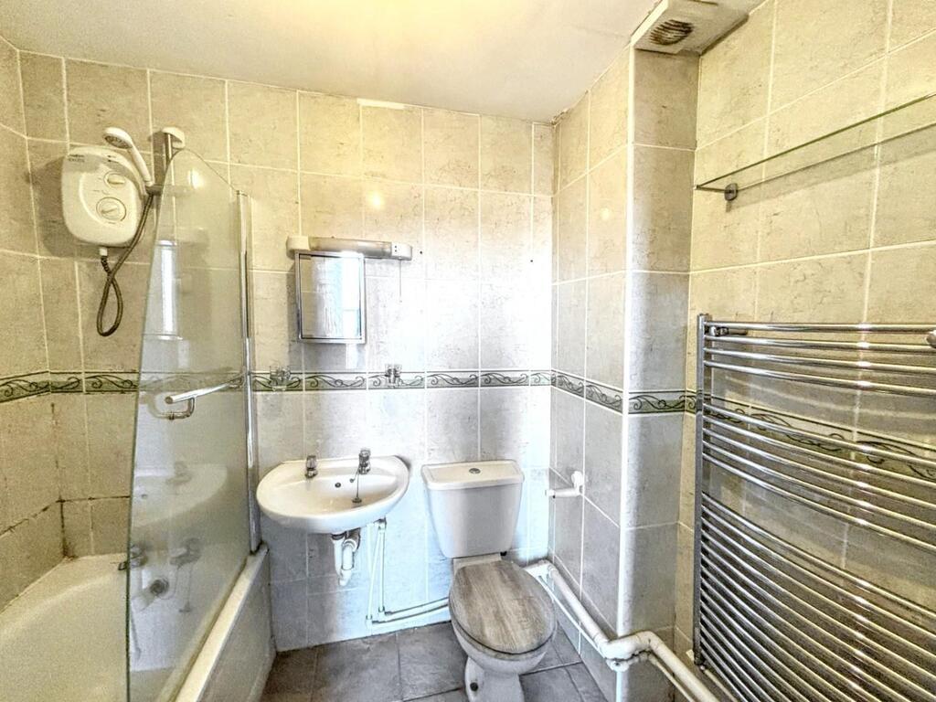 Bright tiled bathroom with a bathtub and overhe...
