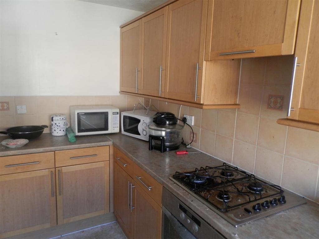 Compact fitted kitchen with light wood cabinets...