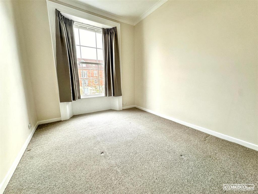 Bright, neutral bedroom with a large bay window...