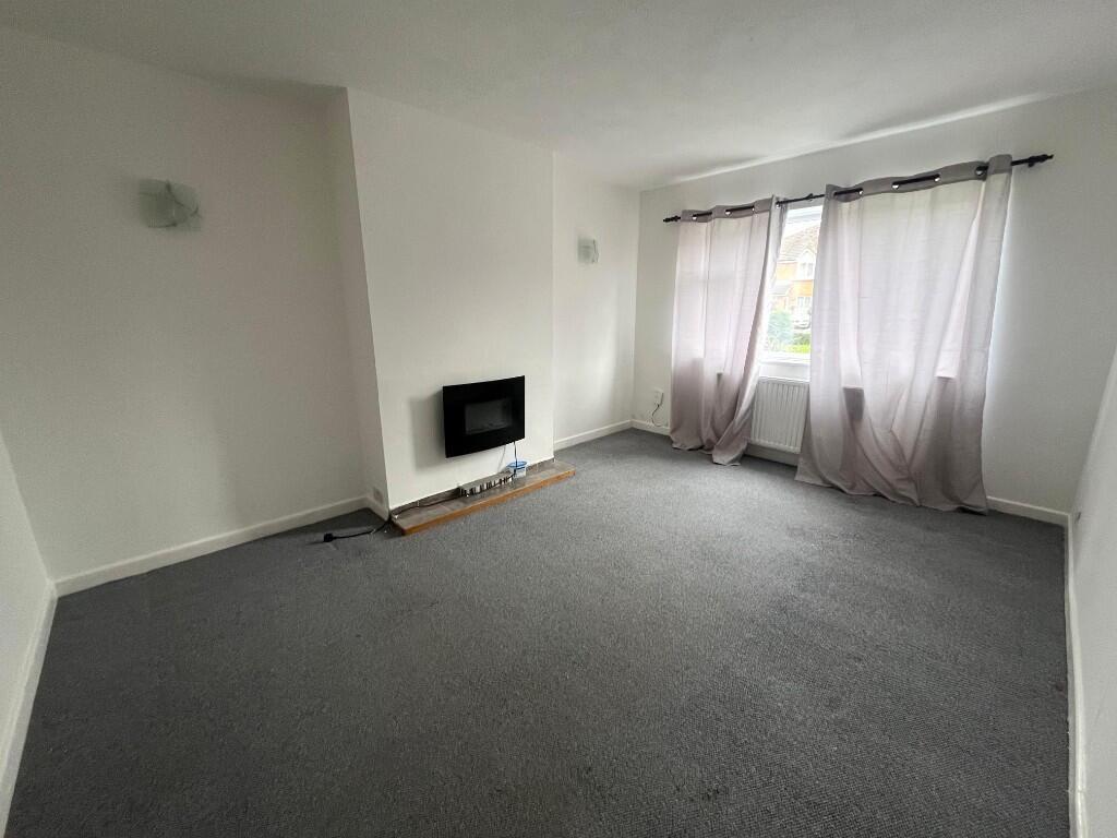 Bright, neutral living room with a wall-mounted...