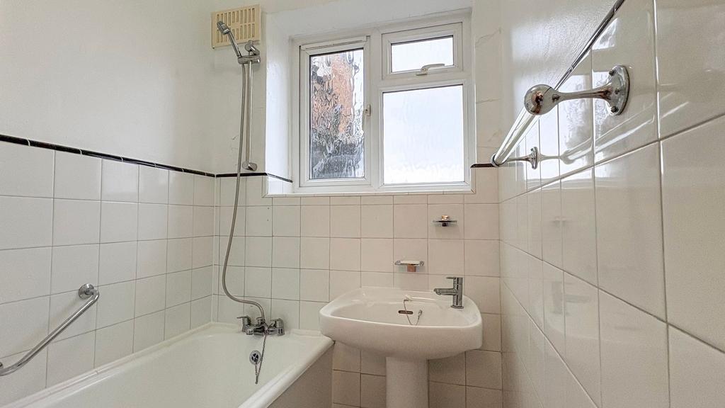Bright, clean bathroom with white tiles, a bath...