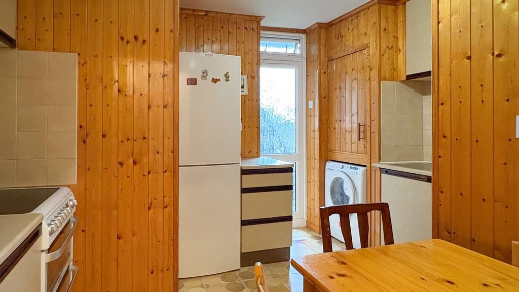 Warm, panelled kitchen with freestanding fridge...