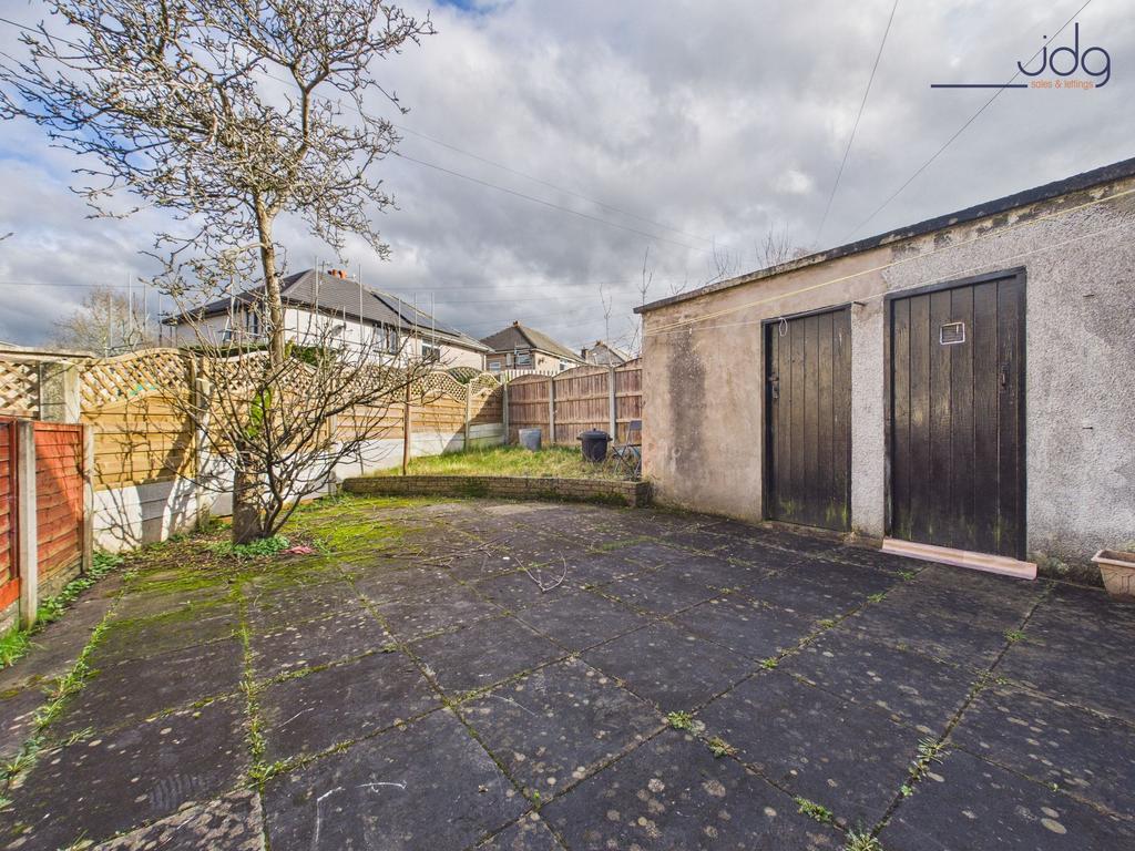 A spacious paved garden with raised lawn and...