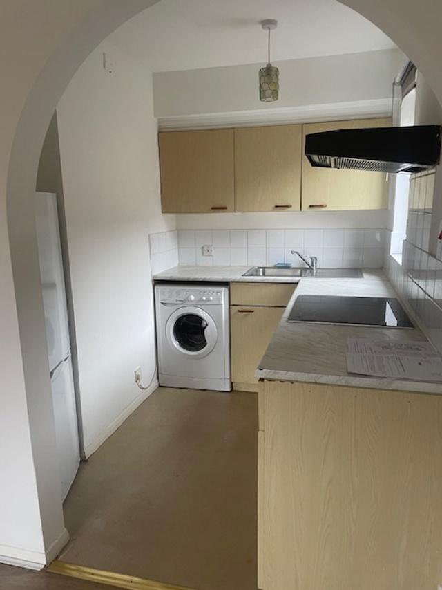 Compact galley kitchen with light wood cabinets...