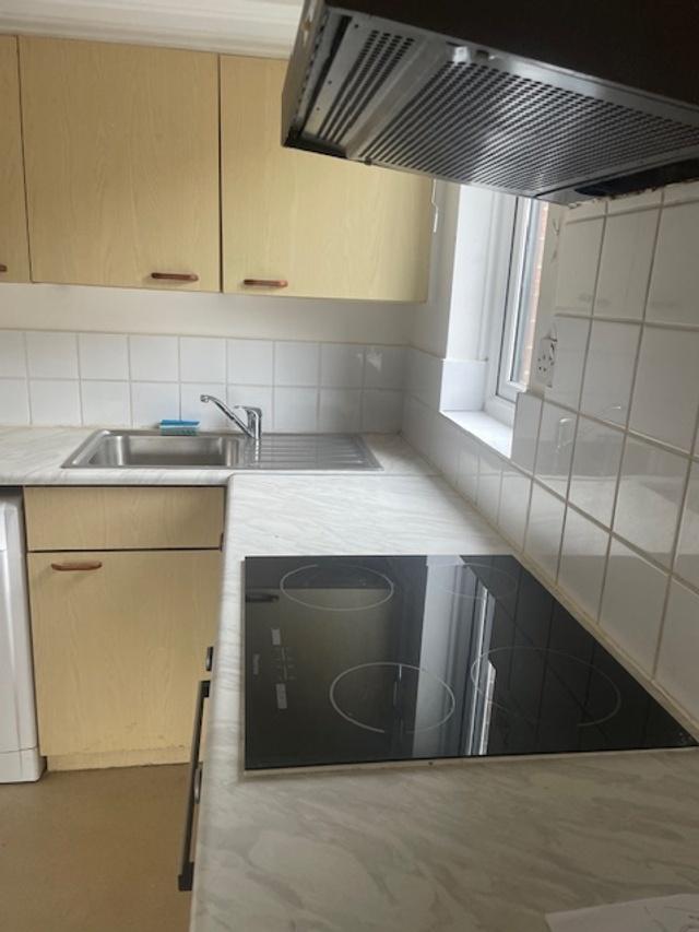 Compact fitted kitchen with light wood cabinets...