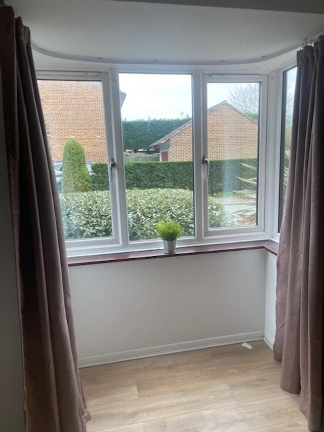 Bright front-facing bay window with neat curtai...