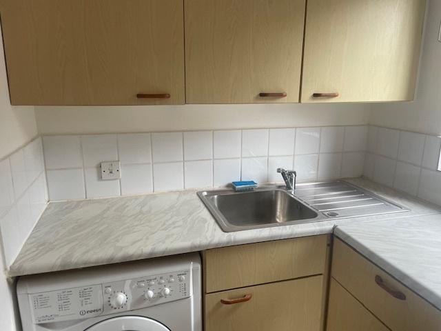 Compact fitted kitchen with light wood cabinets...