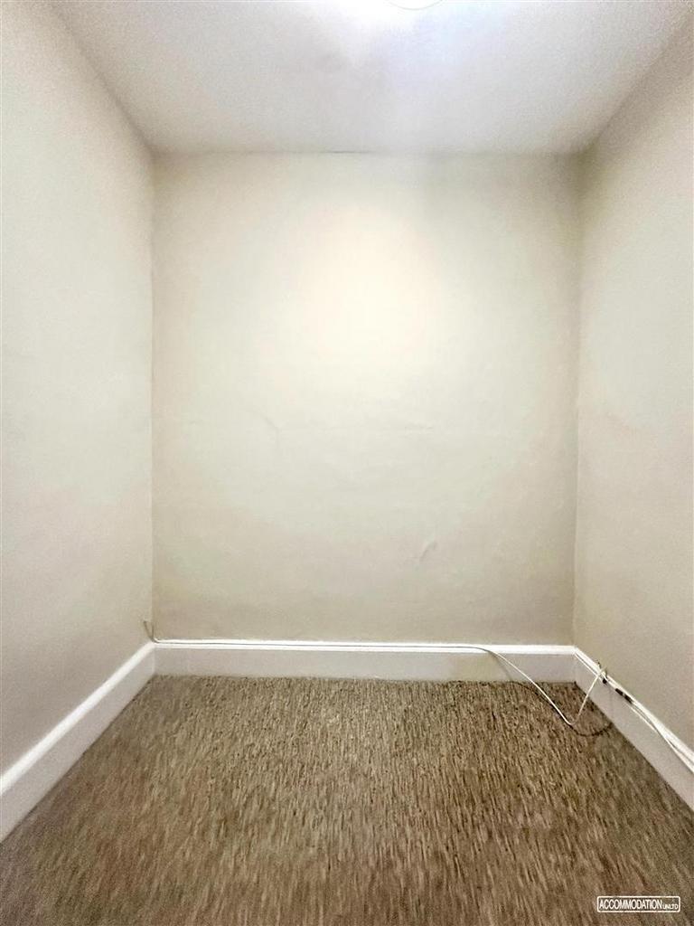 Small tidy room with neutral walls and carpet...