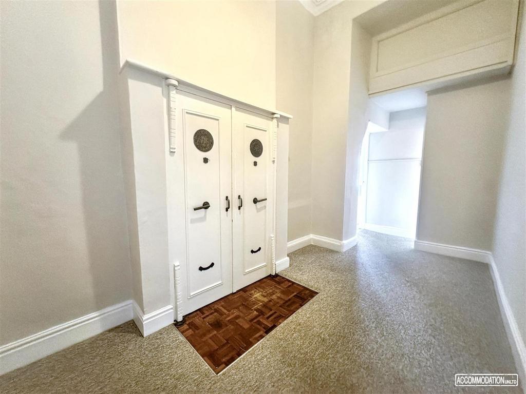 Bright, neutral hallway with feature storage do...
