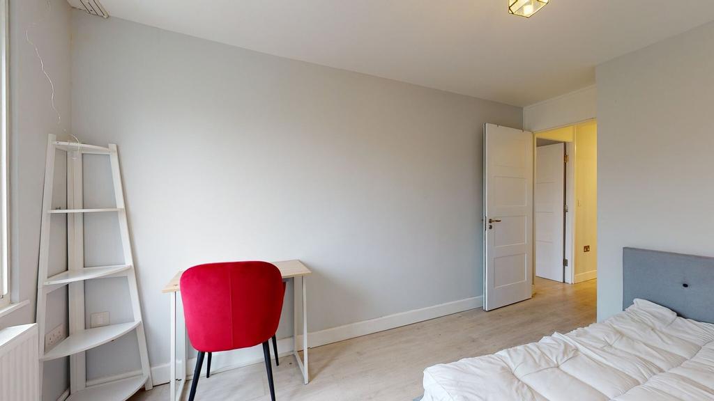 Bright, simply furnished bedroom with a comfy d...