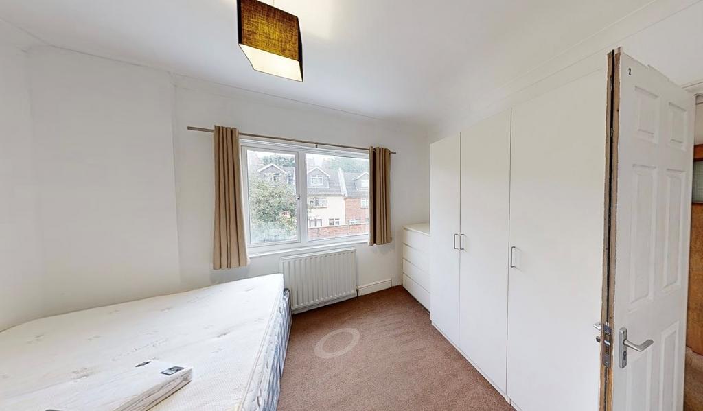 A well-lit bedroom with a large window allowing...