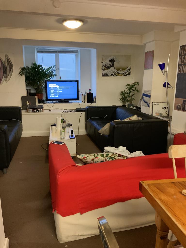 Bright communal lounge with multiple sofas arra...