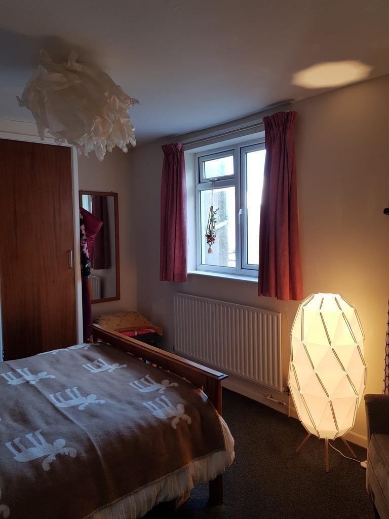 Cosy double bedroom with a wooden bed, soft pat...