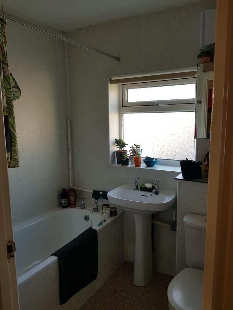 Bright, functional bathroom with a bathtub, ped...