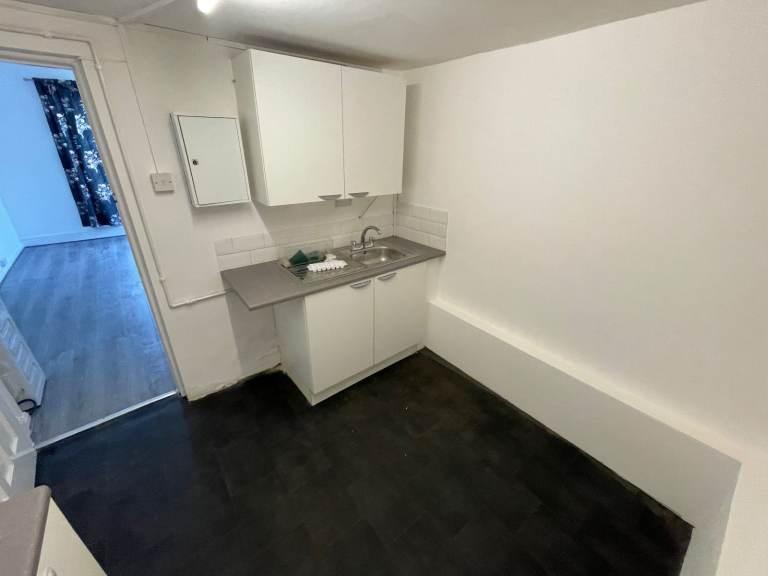 Compact kitchenette with fitted cabinets and si...